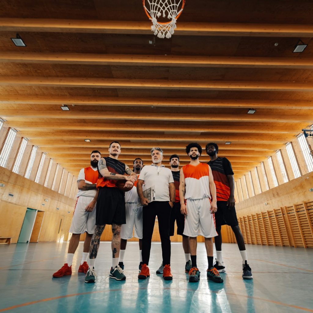 Low angle view of interracial basketball team with senior coach at court.